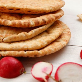 A stack of pitas on a wooden table.