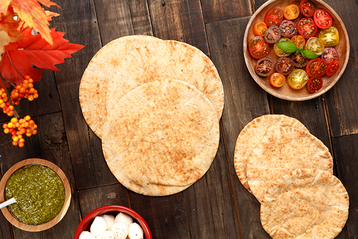 A couple of pitas on a wooden table.